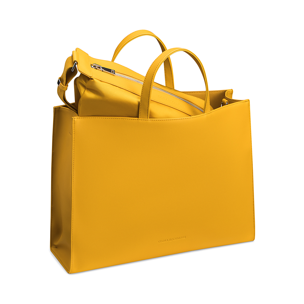 Saffron Tote with the matching detachable mini sling bag coming out of the bag on a white background.
