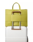 2-in-1 Tote Bag in Avocado showing the sleeve luggage on a white suitcase.