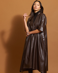 Woman wearing the chocolate brown leather dress against a brown background.
