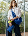 Carla Rockmore modeling the Sling Bag 2.0 in Cobalt Blue. She is wearing the bag as a crossbody bag. She is wearing a white shirt with blue jeans.