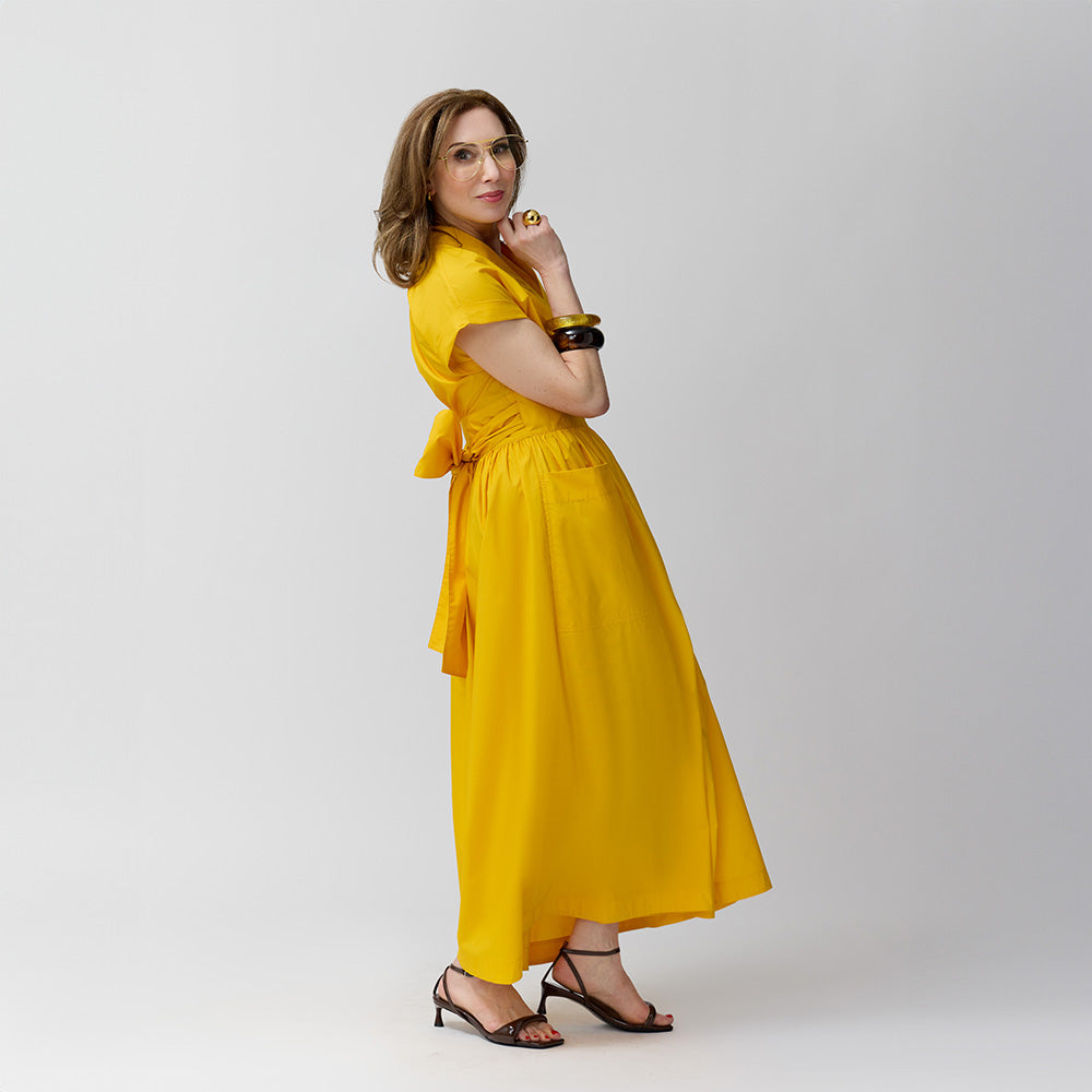 Carla Rockmore wearing the Marigold knee-length wrap shirt dress with a tie at the waist and short sleeves, paired with heels.