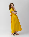 Carla Rockmore wearing the Marigold knee-length wrap shirt dress with a tie at the waist and short sleeves, paired with heels.