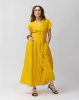 Carla Rockmore modeling the front of the Wrap dress in Marigold short-sleeved maxi dress with a v-neck, standing against a plain background.