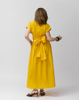 Carla Rockmore modeling the Wrap Dress in marigold showing the back of the dress. The dress is tie like a bow.