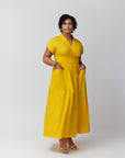 A model with the front of the Wrap dress in Marigold short-sleeved maxi dress with a v-neck, standing against a plain background.