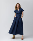 Carla Rockmore in a midnight navy wrap shirt dress with a v-neck and tie back detail, standing against a neutral background.