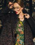 Carla modeling the Leopard Jacquard coat on a florald background.