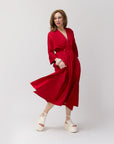 Carla strikes a playful pose in profile while wearing the poppy shirt dress, showing movement and joy with the white platform sandals on a warm-toned neutral set.