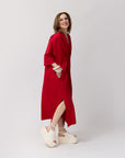 Side view of Carla modeling the shirt dress in vibrant poppy, showing the silhouette and mid-calf hem, with her white platform sandals visible against a neutral background.