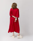 Rear shot of Carla tying the sash of the poppy shirt dress at the back, highlighting the garment’s relaxed fit.
