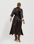 Carla wearing the chocolate brown vegan leather dress showing the back of the dress on a white background.