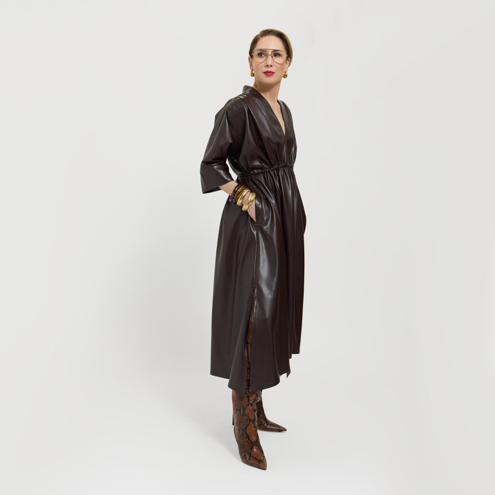Carla wearing the chocolate brown leather dress tied on the back, on a white background