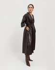 Carla wearing the chocolate brown leather dress tied on the back, on a white background