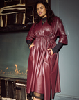 Woman in the Merlot vegan leather dress standing in front of a fireplace.
