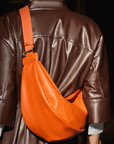 A model wearing the Mini Sling Bag in Burnt Sienna.