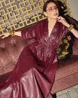 Carla modeling the Everywhere Everyday Shirt Dress in Merlot sitting on a patterned couch.