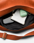 Mini Sling Bag in Burnt Sienna with a phone, wallet, and green case inside on a white background.
