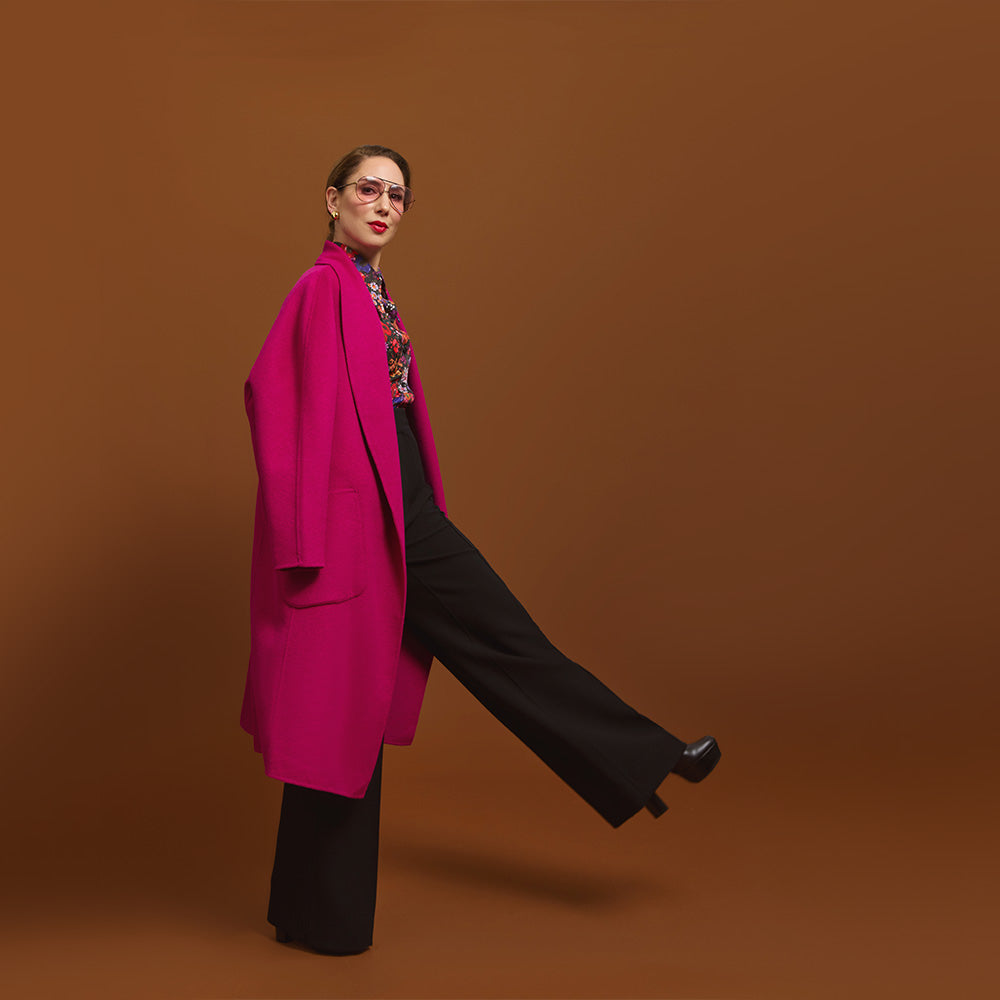 Carla modeling the Indispensable Car Coat Wool Blend in Orchid coat on a brown background. Its showing the pockets in front of the coat.