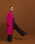 Carla modeling the Indispensable Car Coat Wool Blend in Orchid coat on a brown background. Its showing the pockets in front of the coat.