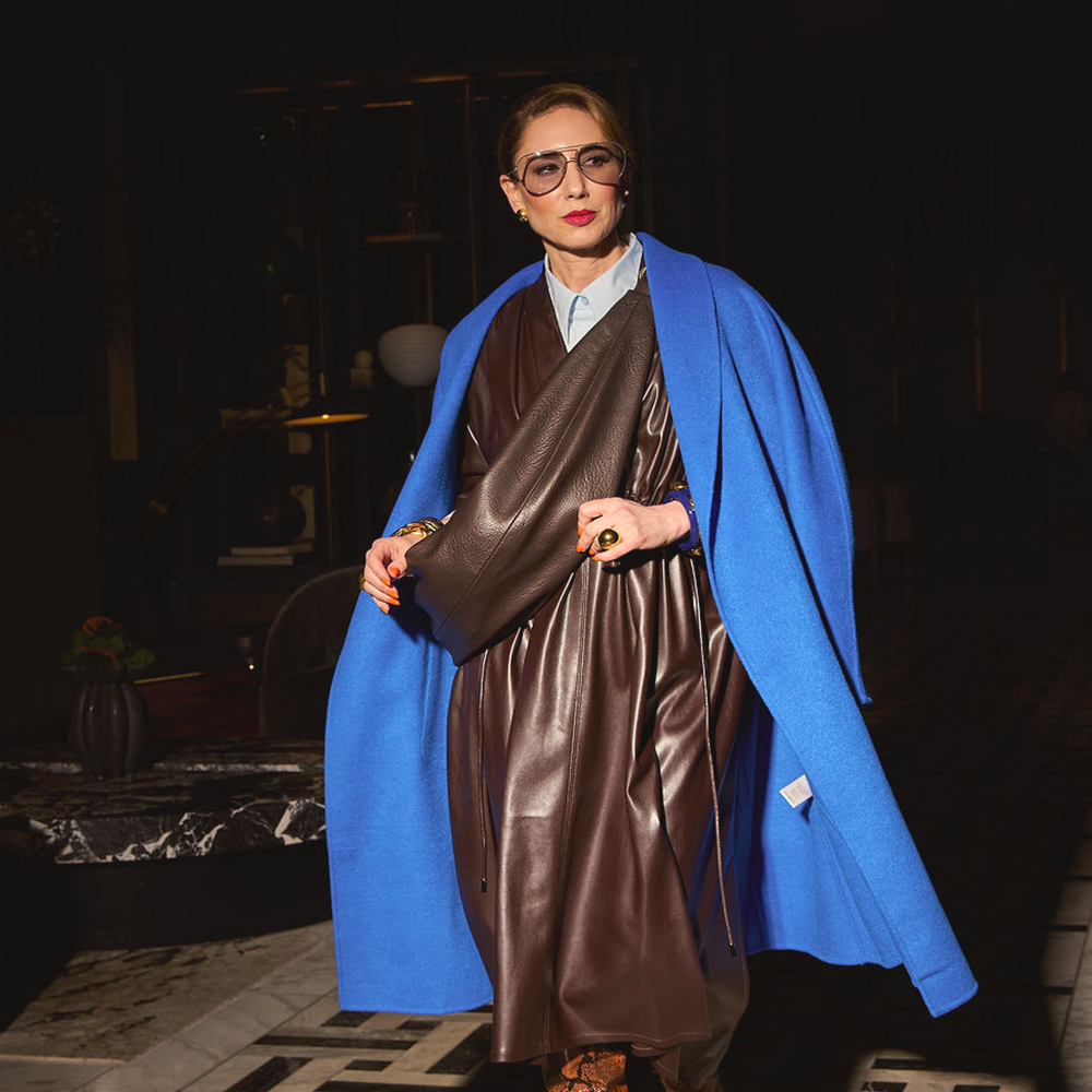 Carla wearing the coat in Cobalt and the Sling Bag in Chocolate.