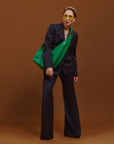 Carla modeling the Sling Bag in Emerald Green on a brown backgroung.