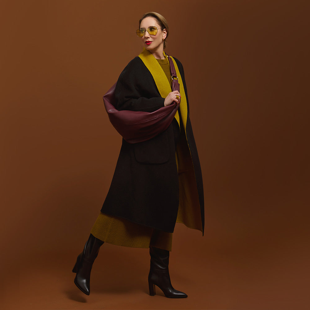 Carla modeling the Merlot Sling Bag on the   black and moss coat.