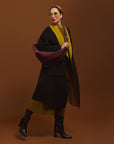 Carla modeling the Merlot Sling Bag on the black and moss coat.