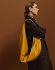Carla modeling the Honeycomb Sling Bag on a brown background.