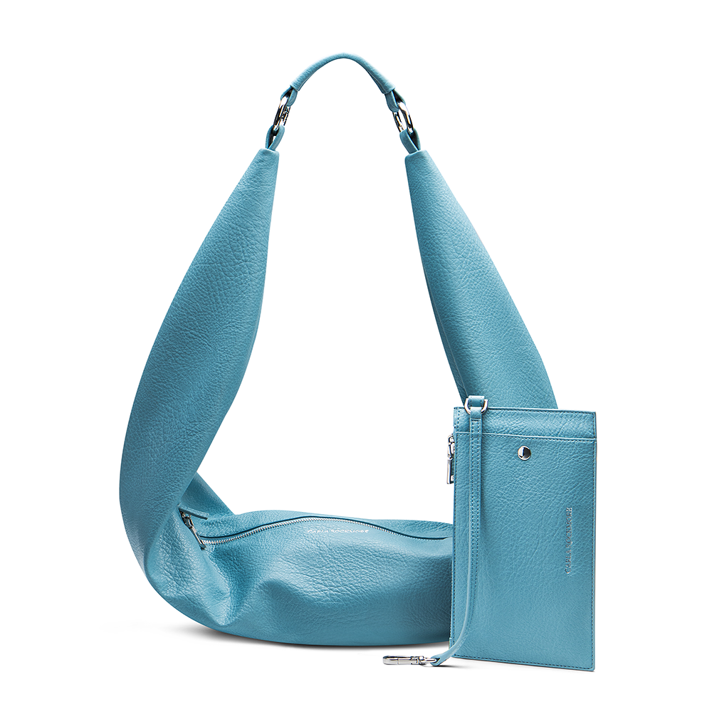 A sky blue sling bag with a textured surface, shown with an adjustable strap and a detachable wristlet pouch. The bag is zipped up on a white background.