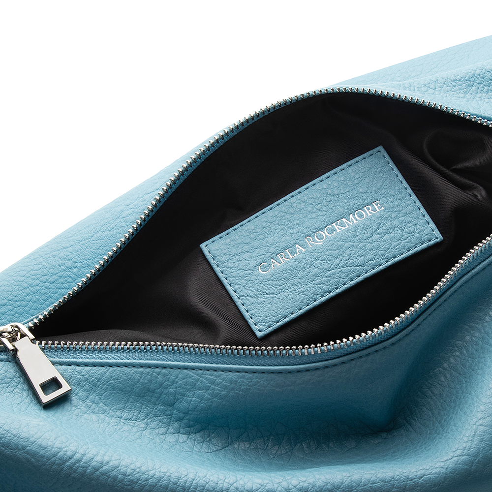 Close up of the Sling Bag 2.0 in Sky Blue
 Bag showing details of the  vegan leather texture. Also, the inside of the bag which is black.