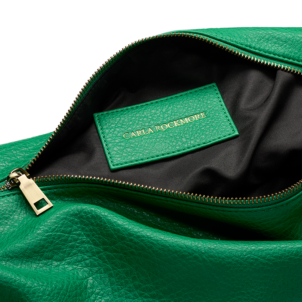 Close-up of the Sling Bag in Emerald Greenwith a visible brand label on a white background.