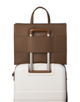 The walnut tote bag on top of a luggage using the luggage sleeve feature on the back of the bag that allows for convenient attachment to luggage.