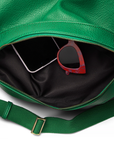 Interior of the emerald green mini sling bag shown with a pair of sunglasses inside, illustrating the bag’s functional storage space.