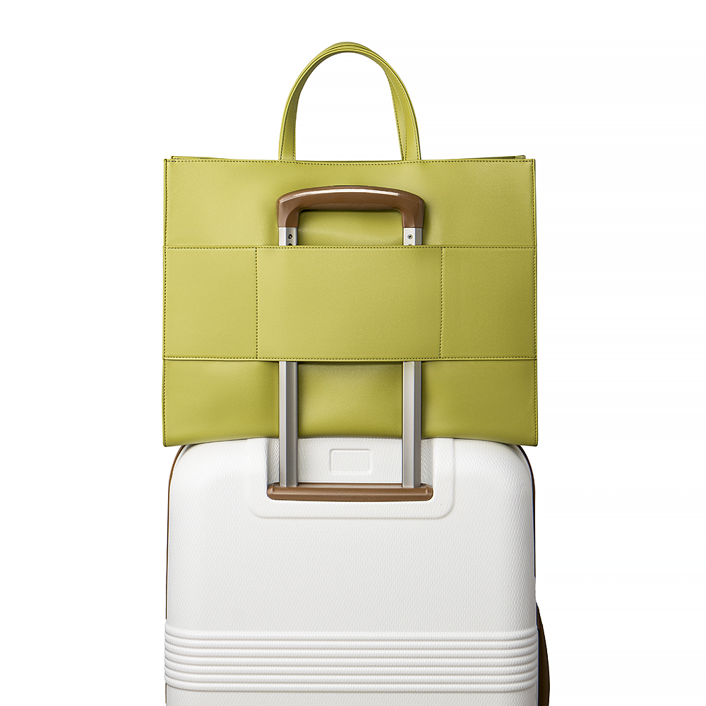 2-in-1 Tote Bag in Avocado showing the sleeve luggage on a white suitcase.