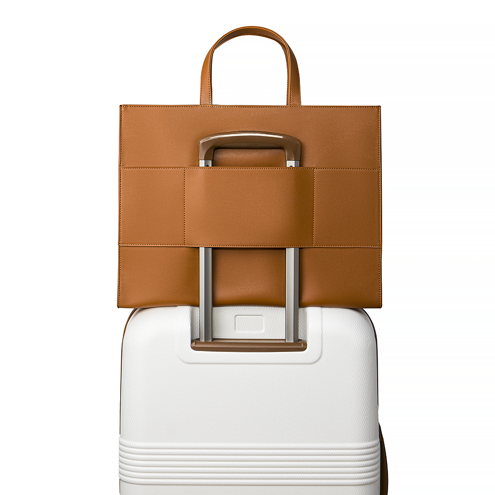 2-in-1 Tote Bag in Caramel showing the luggage sleeve in a suitcase. 
