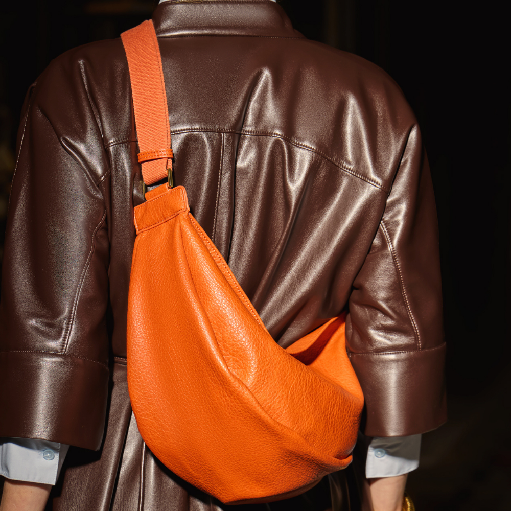 A model wearing the Mini Sling Bag in Burnt Sienna.