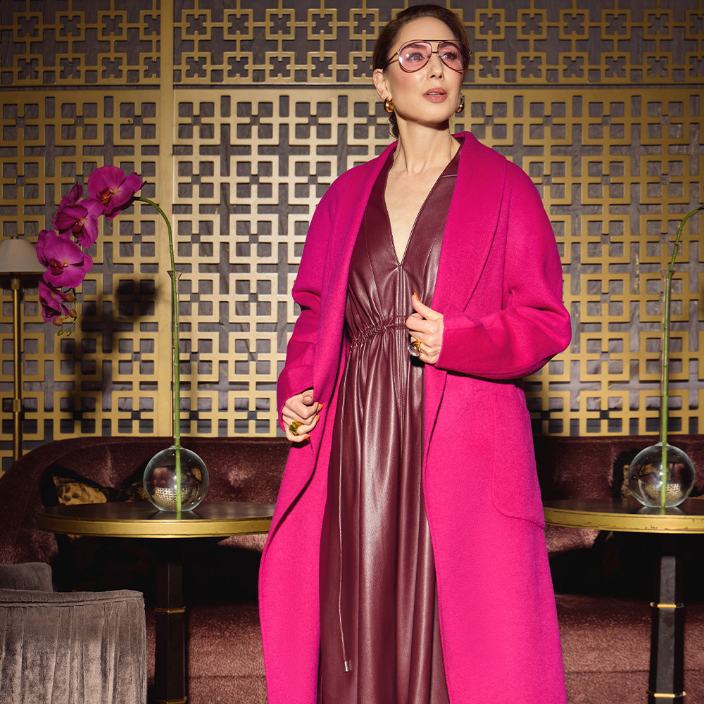 Carla in the Indispensable Car Coat Wool Blend in Orchid over a the vegan leather dress in Merlot an elegant room with decorative elements as background.