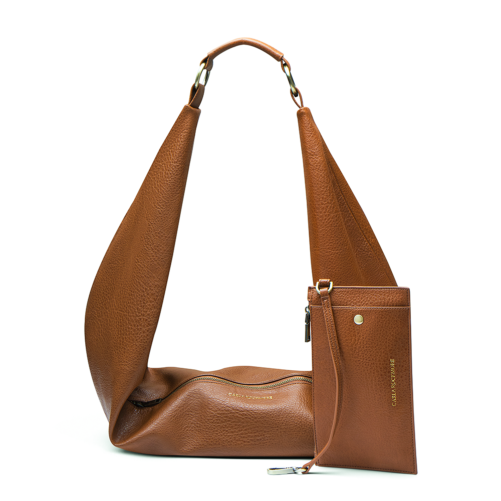 Saddle vegan leather sling bag with a detachable wristlet, displayed against a white background.