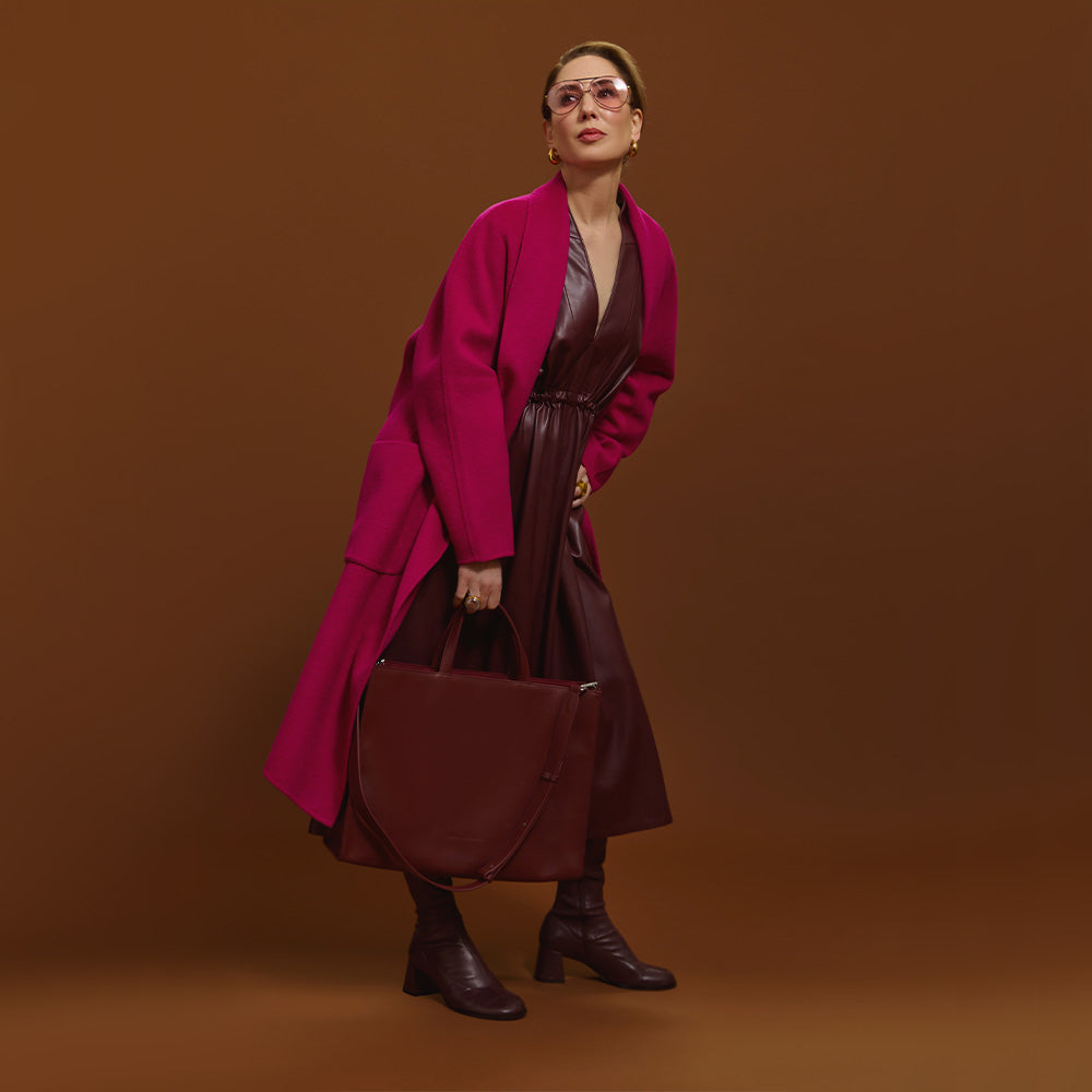 Carla modeling the Cherry Cola Tote Bag and the coat is Orchid on a brown background. 
